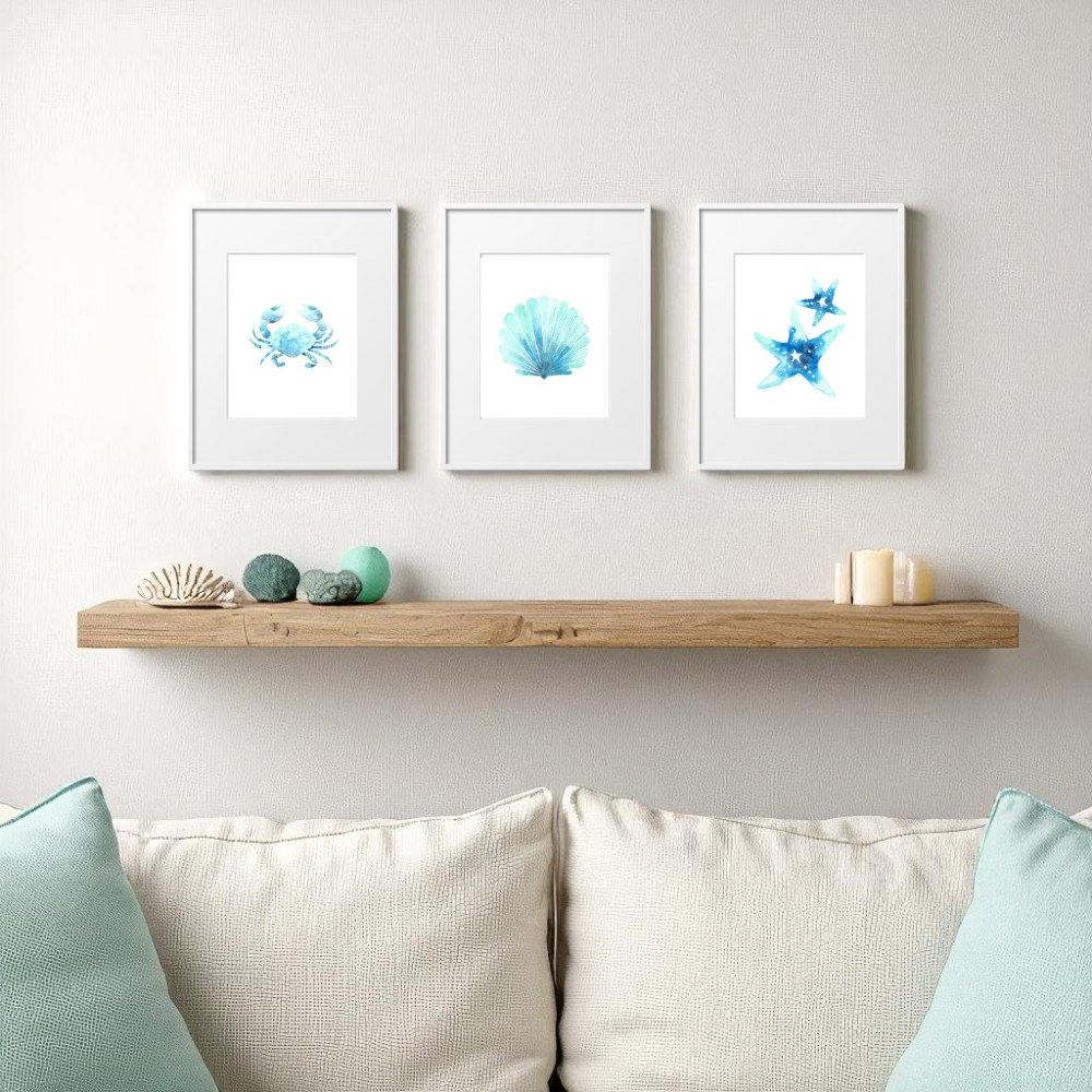 Three 8x10 framed beach prints in white frames above a wooden shelf, styled with turquoise accents, sea decor, and a coastal cream sofa.