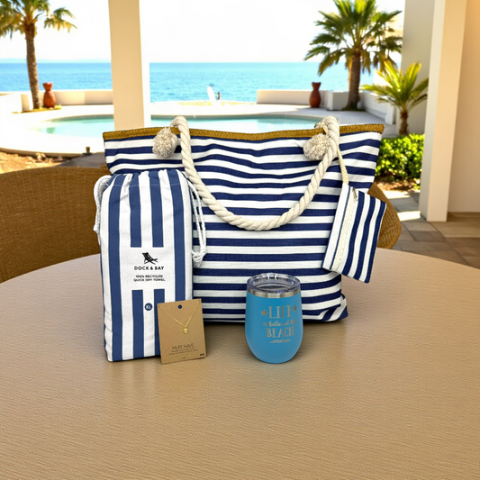 Navy Beach Lover Gift Set displayed on a resort patio with ocean view. Includes a navy striped beach bag, matching towel, ocean blue tumbler, and sea turtle necklace. A calm, coastal beach lover gift idea that makes a thoughtful and practical choice for women who love the beach.