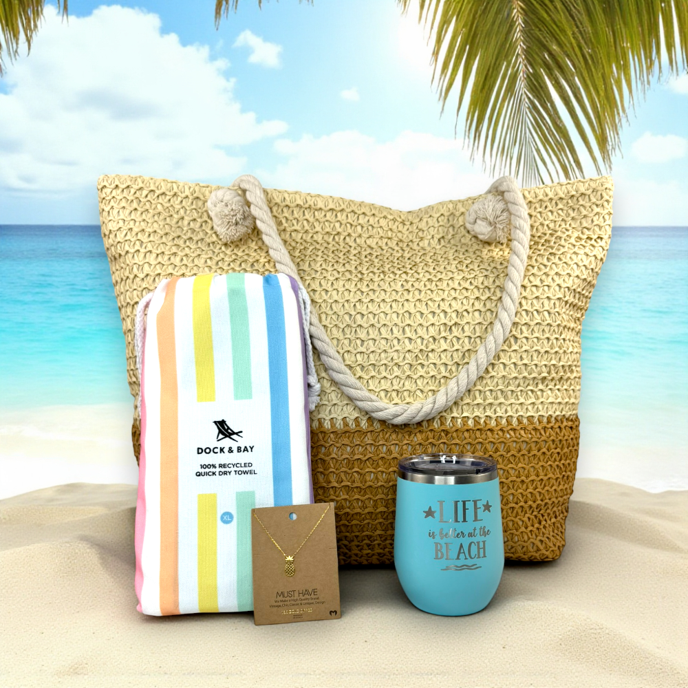 beach lover gift set in pastel rainbow including a straw tote, striped towel, necklace, and tumbler on sand with ocean and palm tree background.