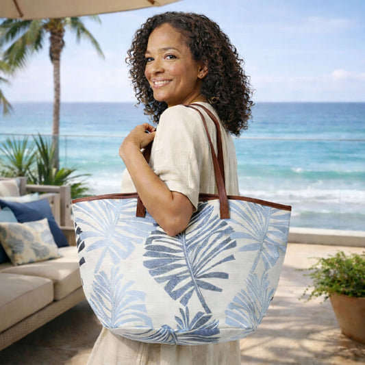 Woman carrying blue palm leaves canvas beach tote with zipper on a beach patio.