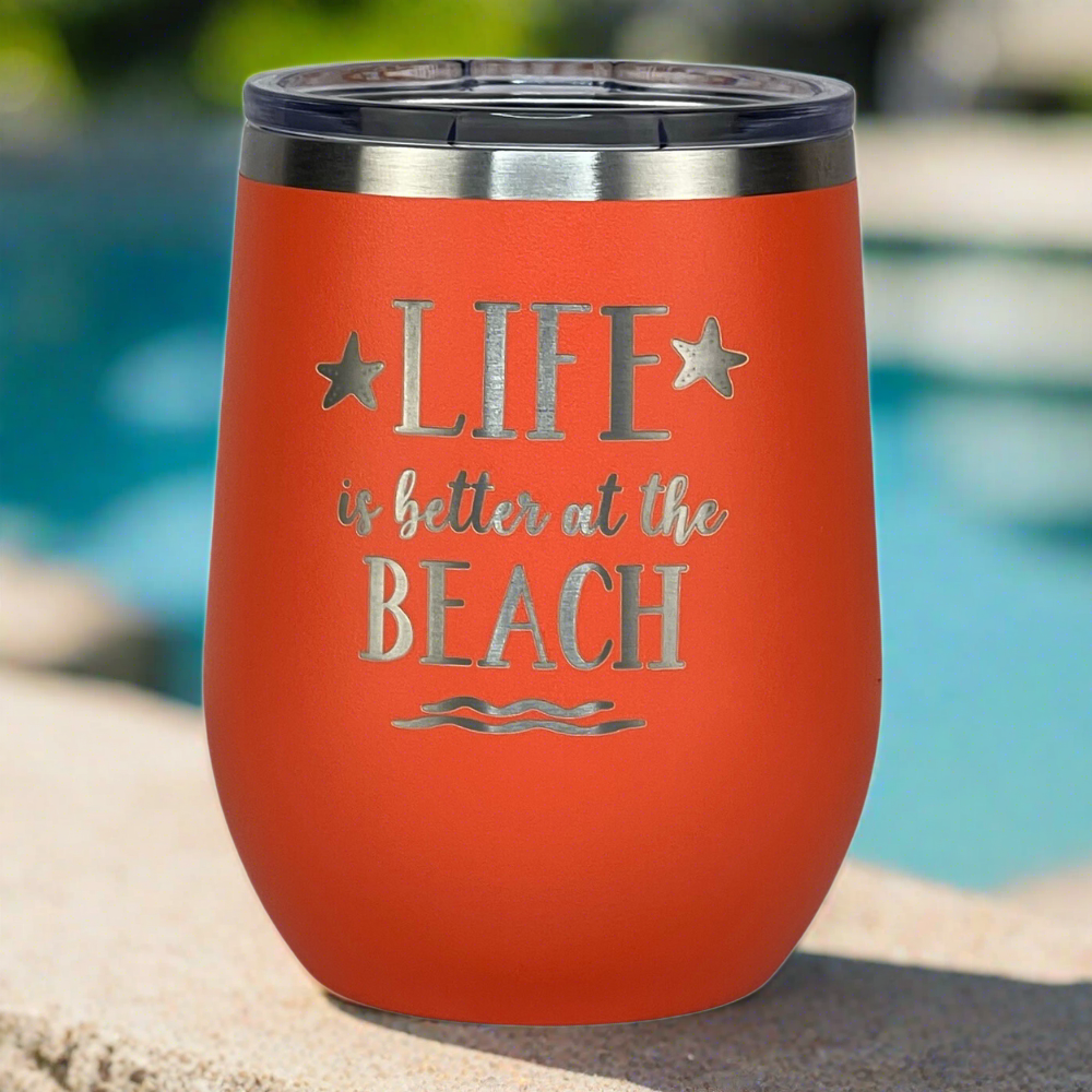Close-up of coral-colored insulated tumbler with secure lid and beach-themed engraving