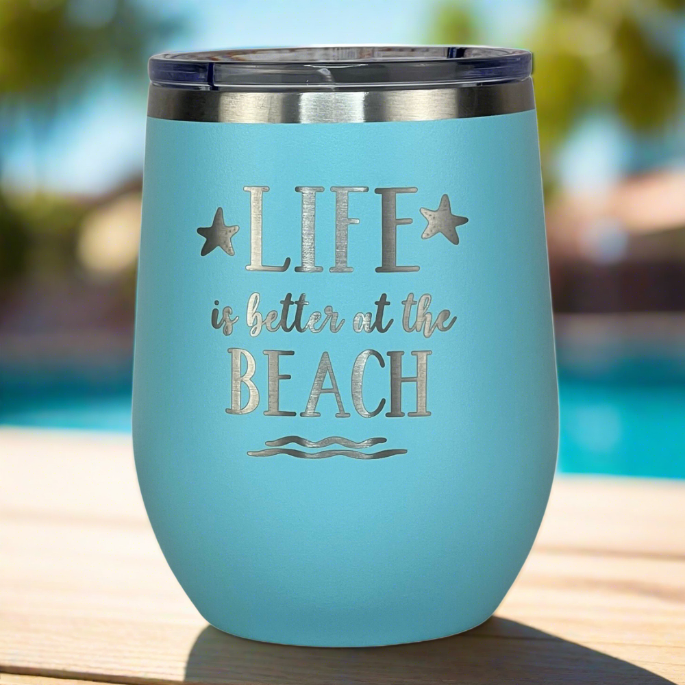 Teal insulated wine tumbler placed near a pool, engraved with “Life is Better at the Beach.”