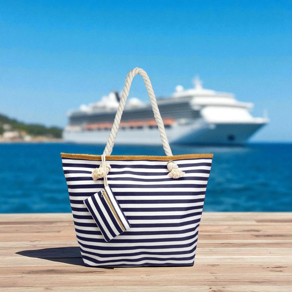 Navy and white striped beach tote bag with rope handles and coin purse placed on a dock with a cruise ship in the background