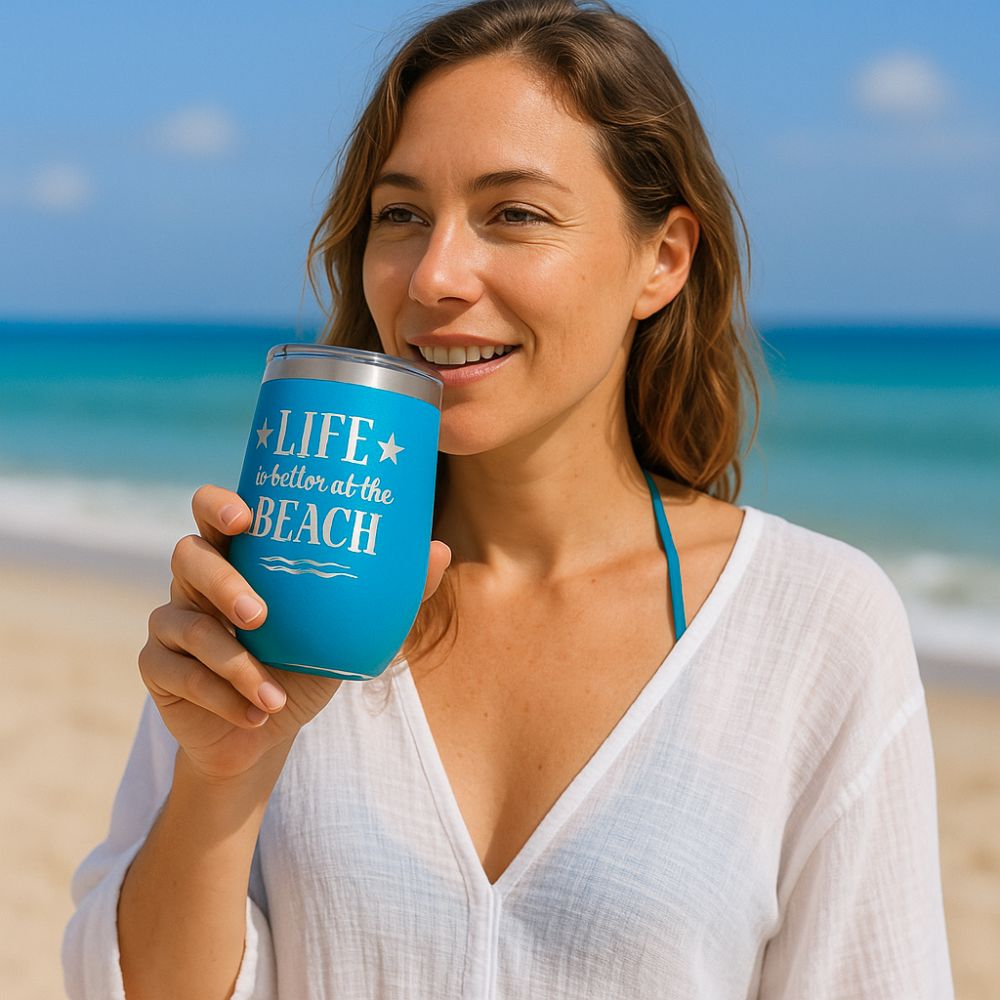 woman standing on beach with ocean waves in the background holding ocean blue metal wine tumbler