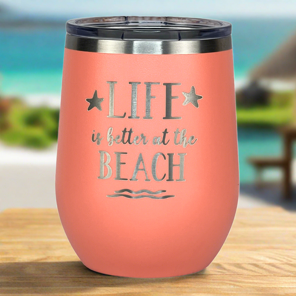 Peach metal tumbler with secure lid, perfect for cocktails, coffee, and beach drinks, displayed on a sunny table at the beach