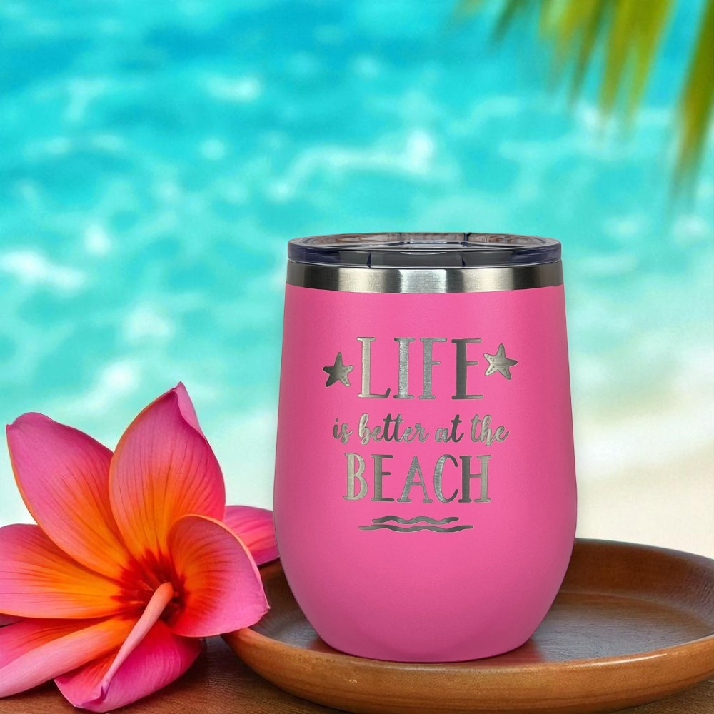 Pink insulated tumbler from the Pink Beach Lover Gift Set with 'Life is better at the Beach' text next to a tropical flower with a beach background.