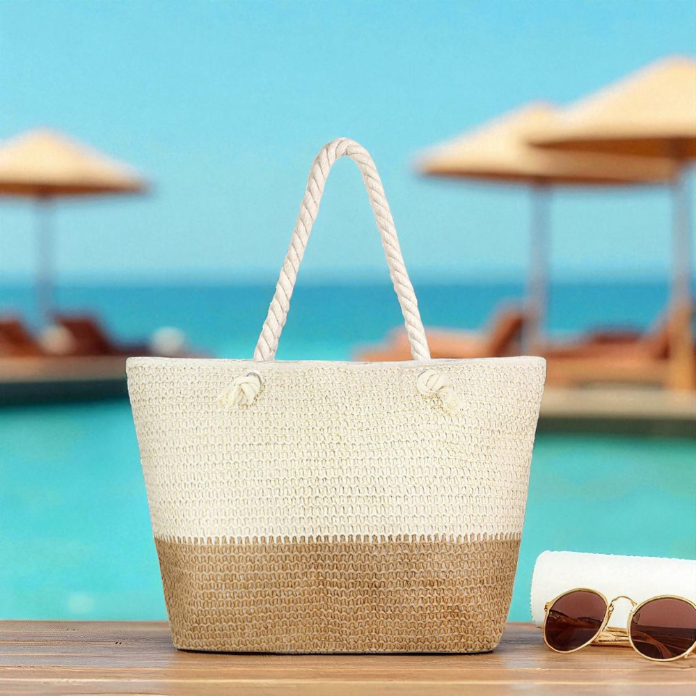 Neutral straw beach bag beside white towel and gold sunglasses on sunny dock with clear turquoise ocean and cabanas in the background in a beach setting.