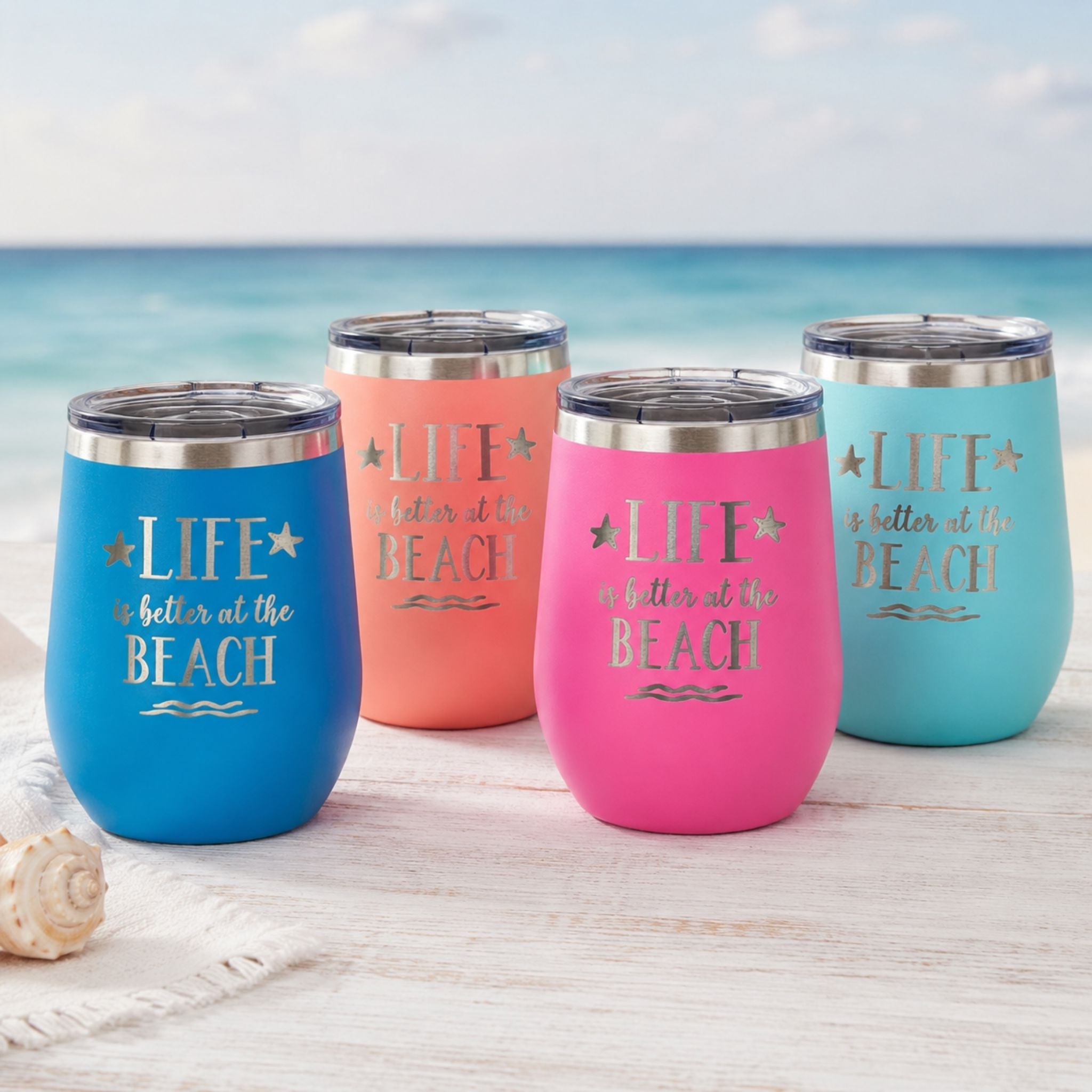 teal metal wine tumbler on a beachside table next to a beach lounge chair with the ocean in the background.
