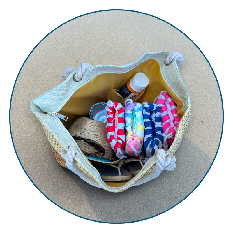 Large straw beach bag filled with towels and sunscreen on a bright, neutral background.