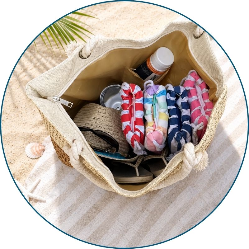Large straw beach bags with zipper holding towels, sunscreen, snacks, and other beach bag essentials.