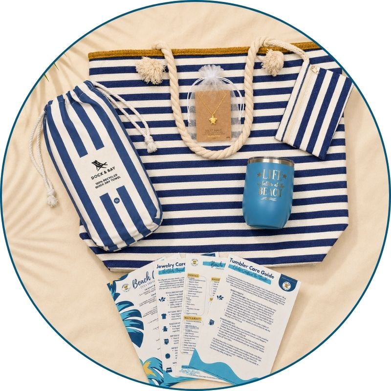 Navy beach bag gift set flat lay with striped beach bag, navy striped towel, blue tumbler, gold-dipped sea turtle necklace and printed bonus cards.