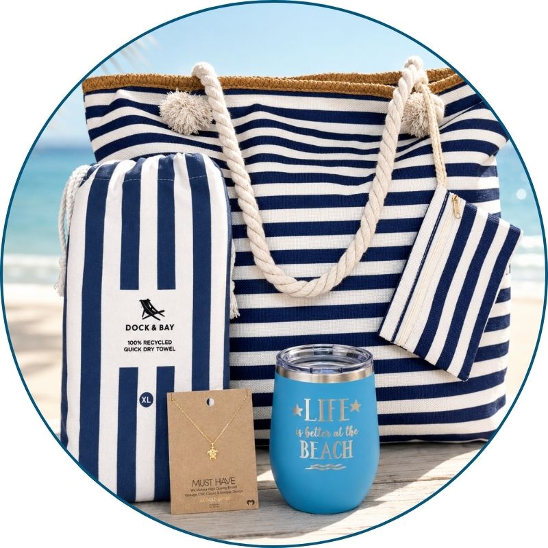 Navy beach lover gift set styled by the ocean with navy striped beach bag, striped towel, blue tumbler and gold-dipped sea turtle necklace.