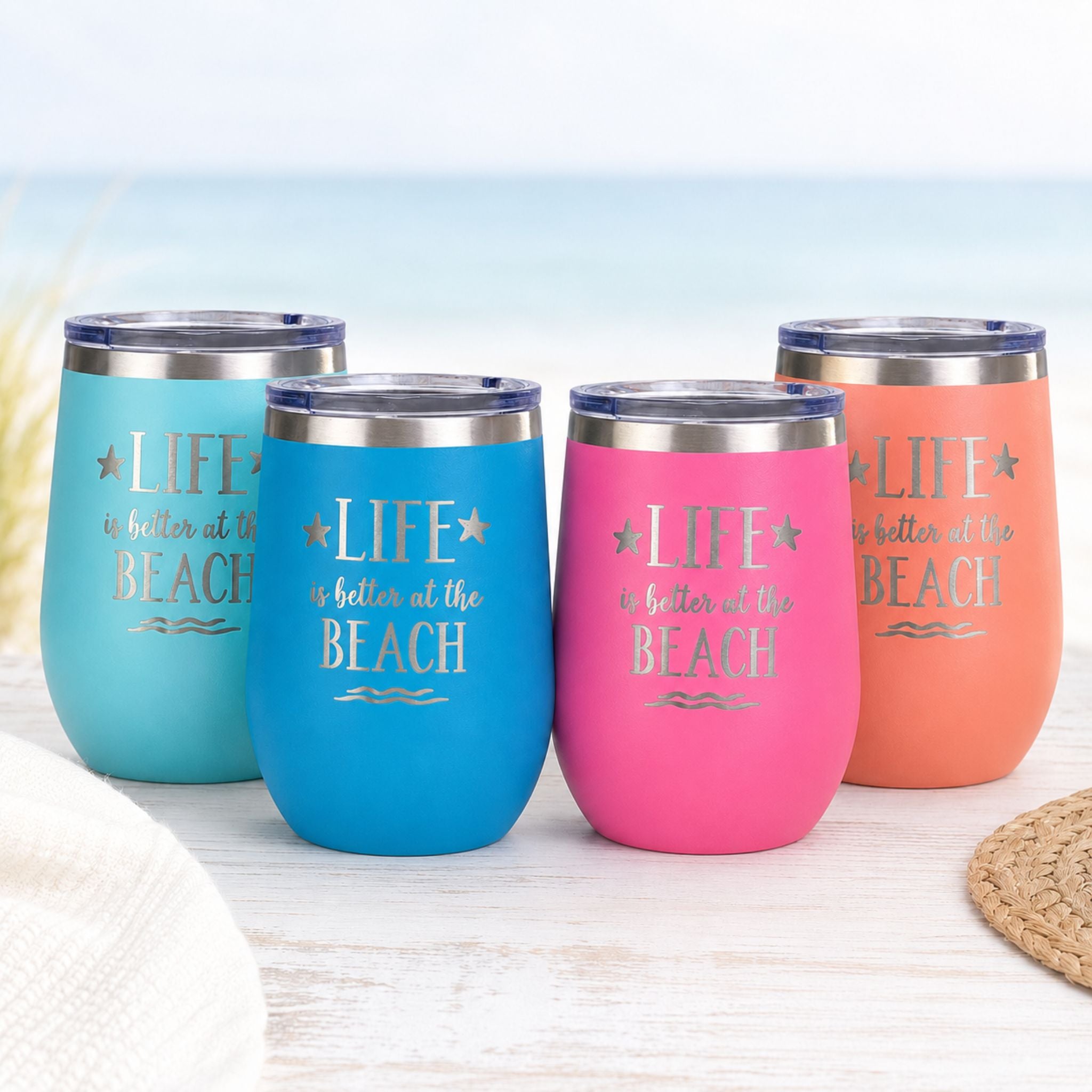 Beach insulated wine tumblers with lids in teal, ocean blue, pink, and peach on a light coastal background