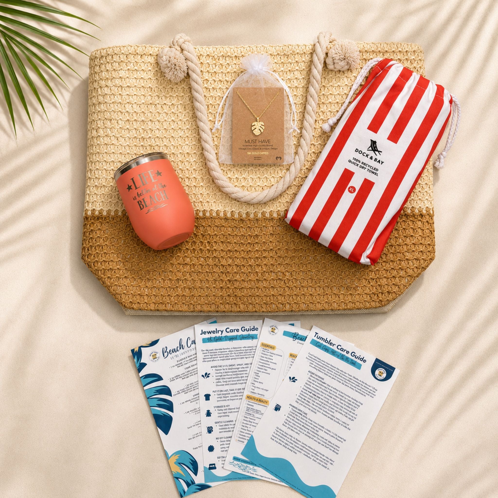 Beach lover gift set flat lay with straw beach bag, coral striped towel, peach tumbler, gold-dipped necklace and bonus cards.
