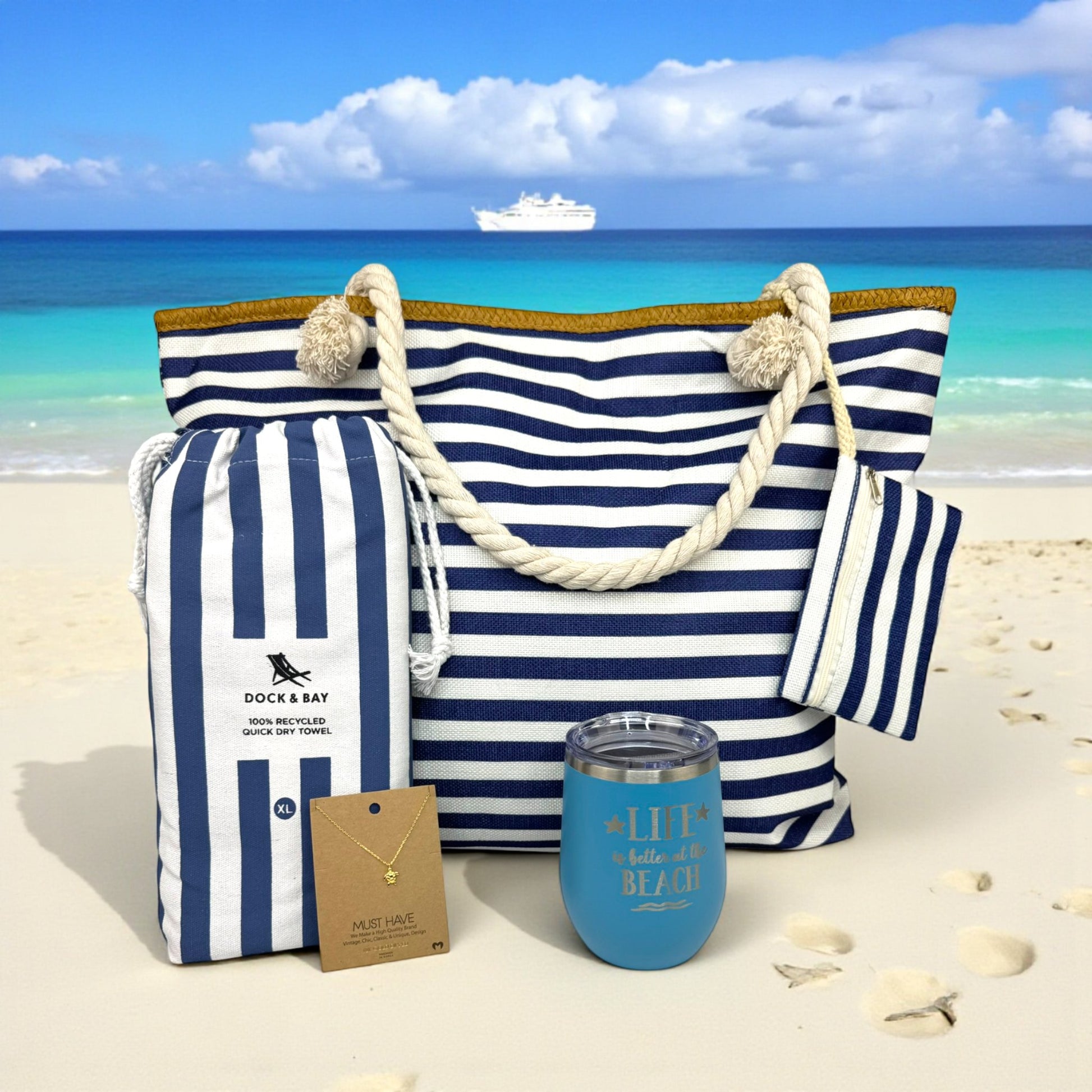 Navy Nautical Beach Lover Gift Set arranged on natural sand with turquoise ocean and cruise ship in the distance. A beautiful, ready-to-gift beach lover beach bag gift set perfect for beach vacations, cruise gifts, or thoughtful gifts for beach lovers any time of year.