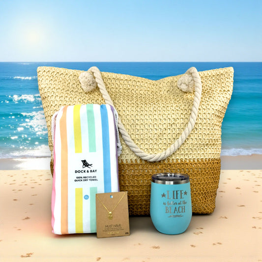Beach Lover Gift Set – Pastel featuring straw beach tote, Dock & Bay pastel towel, teal insulated tumbler, and pineapple necklace arranged on sand beside calm turquoise sea under bright sunshine — thoughtful beach gift for her.