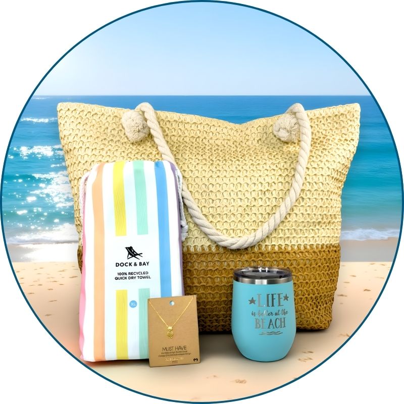 pastel beach lover gift set in a beach setting with towel, tumbler, bag, and pineapple necklace and ocean in the background