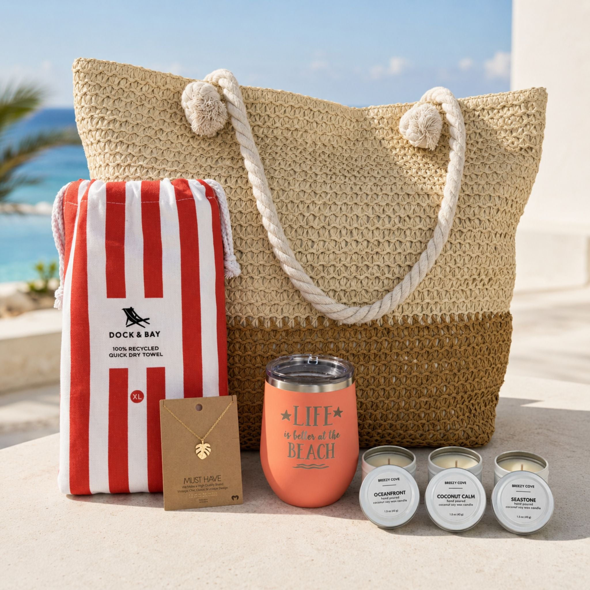 Beach lover gifts under $150 with straw beach bag, striped towel, peach tumbler, gold-dipped necklace and beach candle trio in a luxury beach setting.