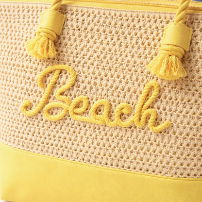 Close-up of yellow “Beach” rope embroidery and zipper top on straw canvas tote bag