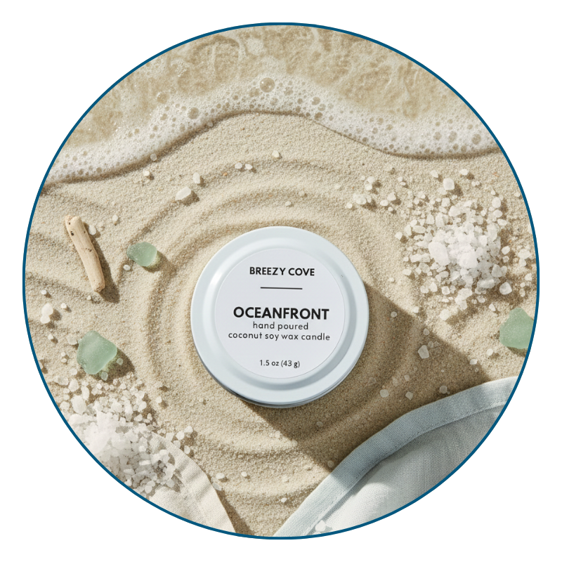 Top-down image of Oceanfront mini candle in white tin on ocean and sand background, a fresh ocean-scented candle.