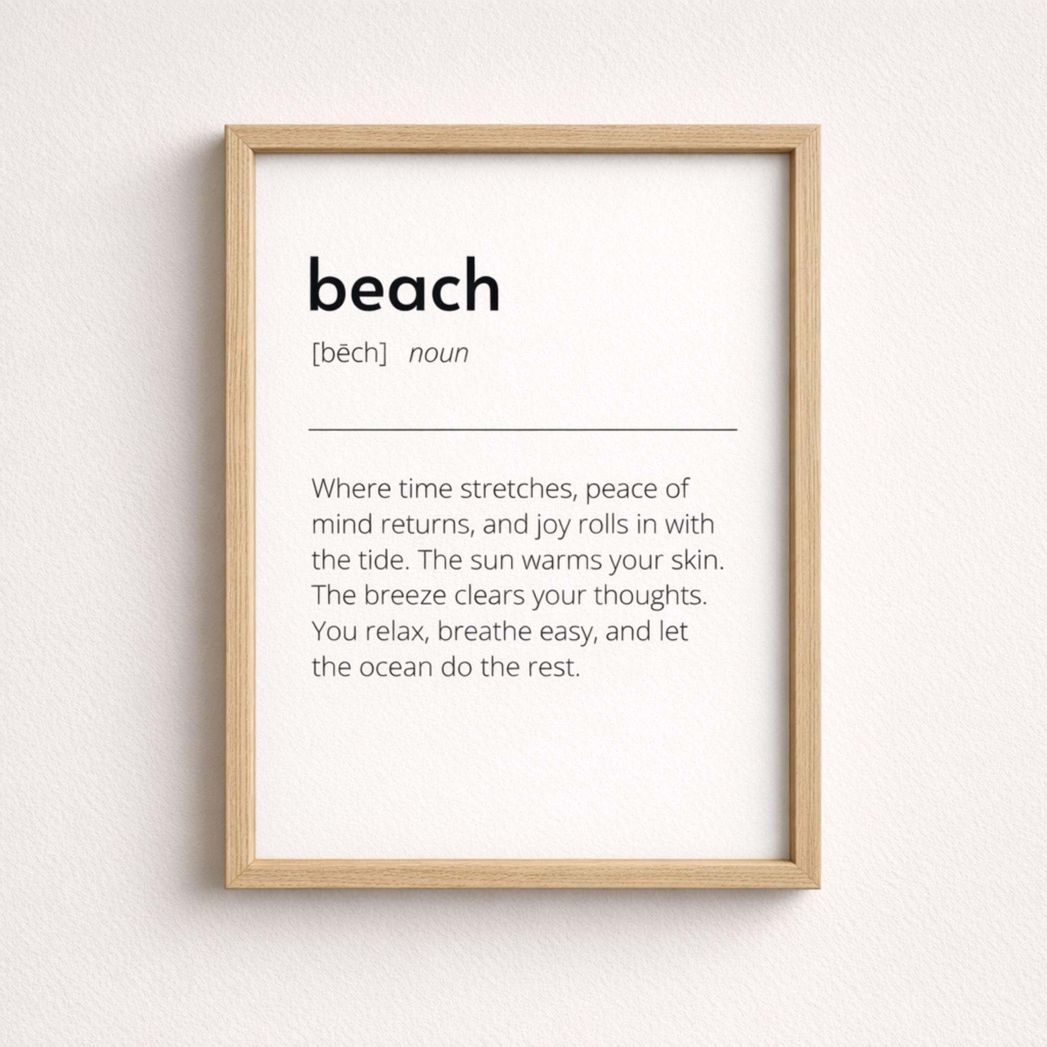 Beach definition art print in light wood frame with minimalist black text on white background