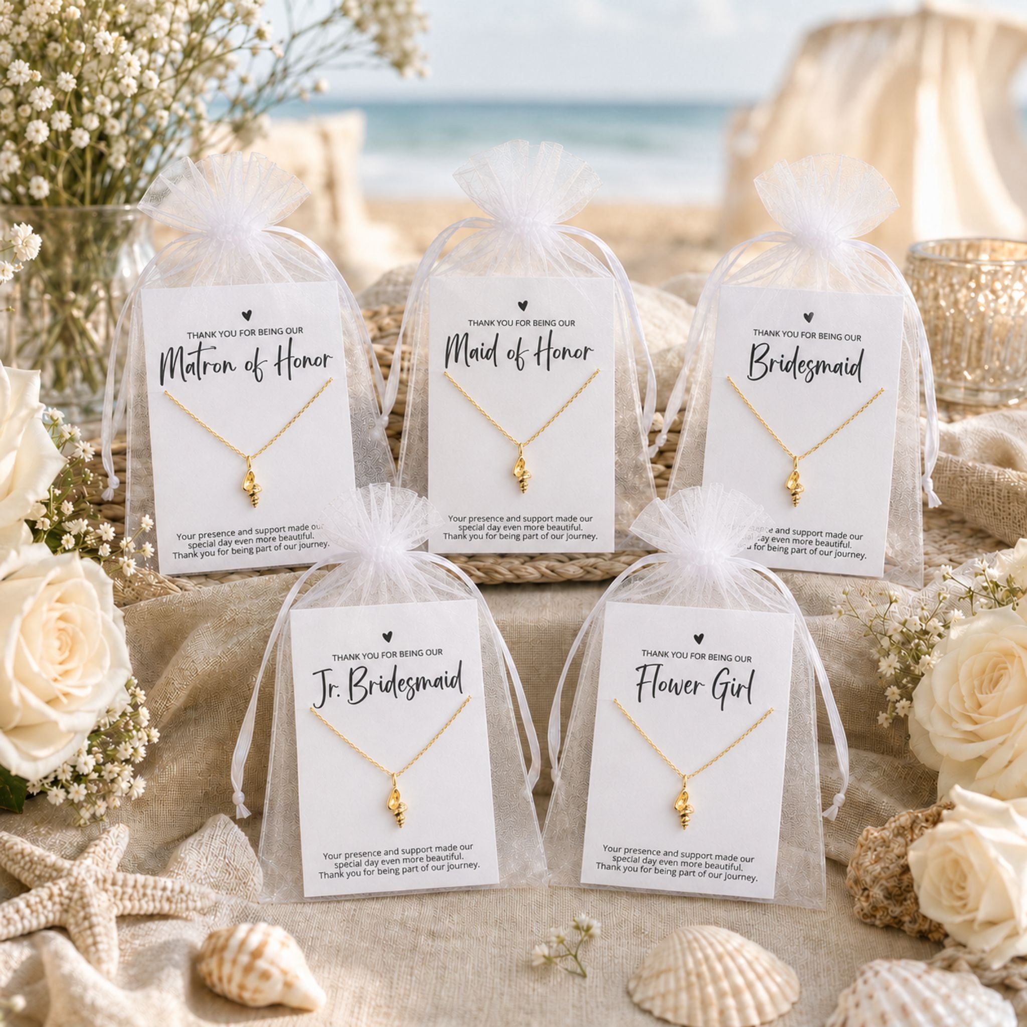 Beach wedding bridal party gifts displayed with coastal conch shell necklace cards and white organza bags on a beach gift table