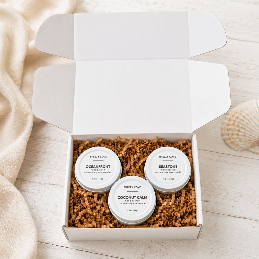 Beachside Mini Candle Trio candle gift set shown open with Oceanfront, Coconut Calm, and Seastone coconut soy candles inside a white gift box.