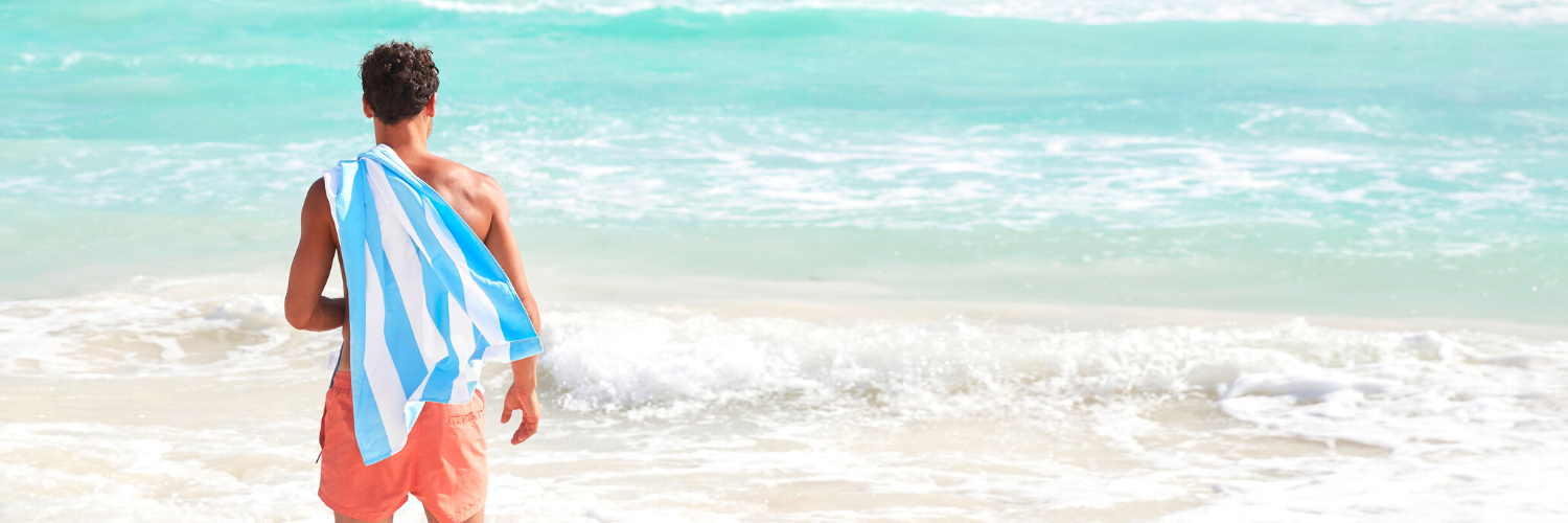 man on beach holding quick dry, sand free beach towel