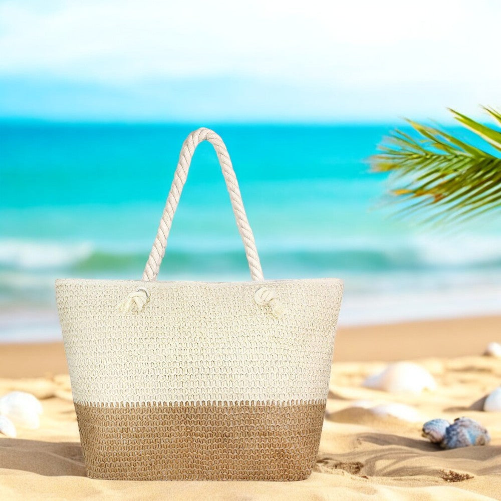 A large straw beach bag with rope handles sits on the sand near the shoreline. 