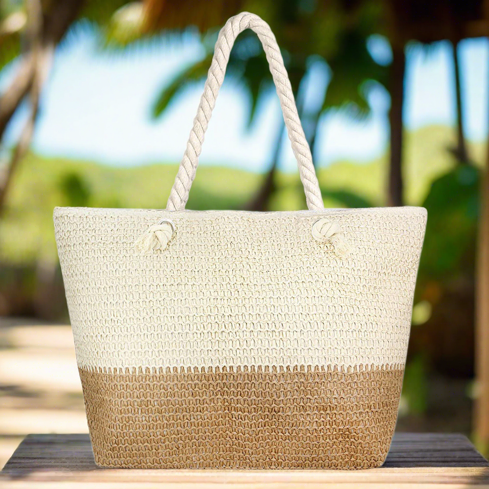 large, oversize beige and tan straw beach bag with zipper and rope handles with palm trees in background