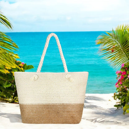 A large straw beach bag with rope handles sits on the sand near the shoreline with palm trees.