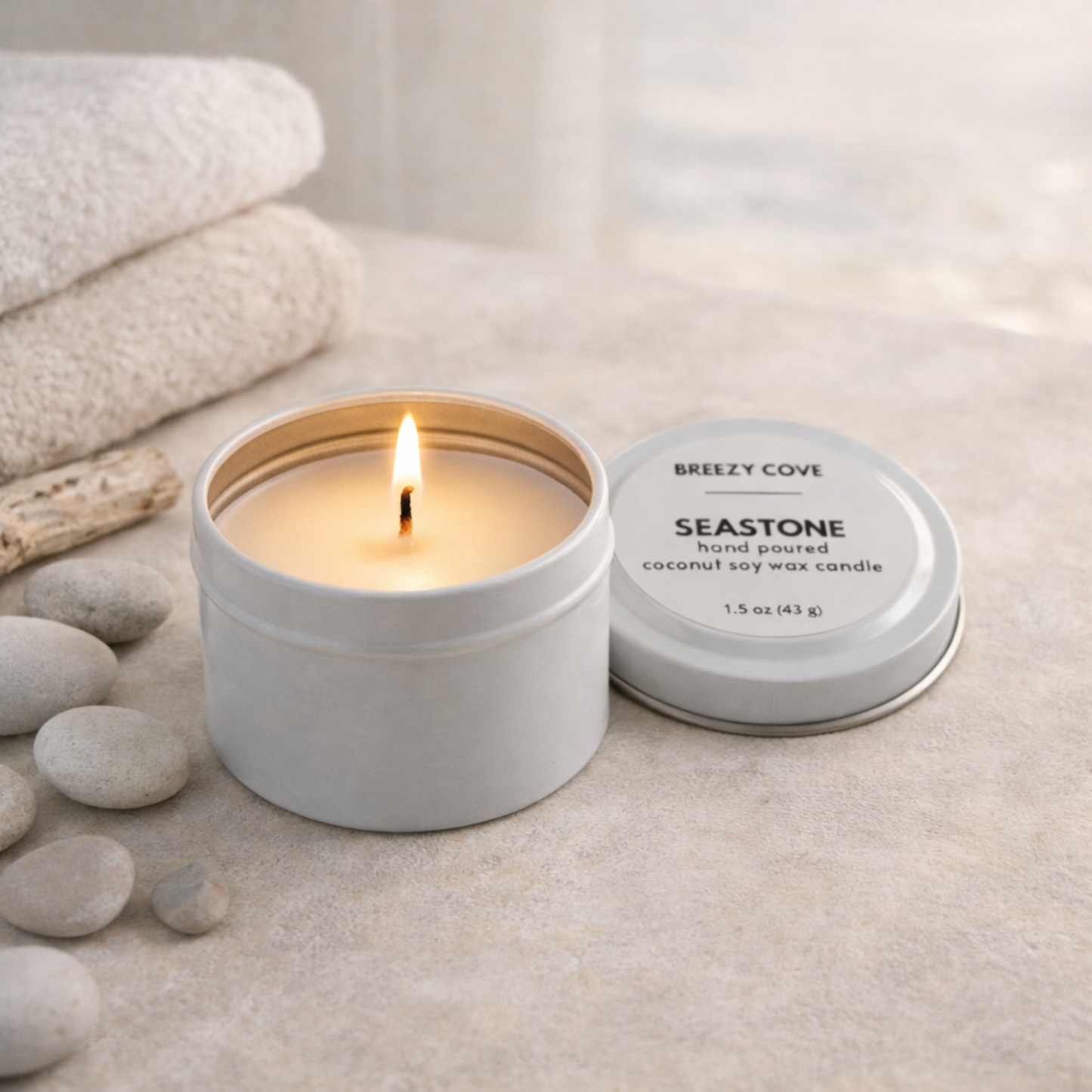 Seastone beach scented mini candle tin with in a beach spa setting for a calm coastal scent.