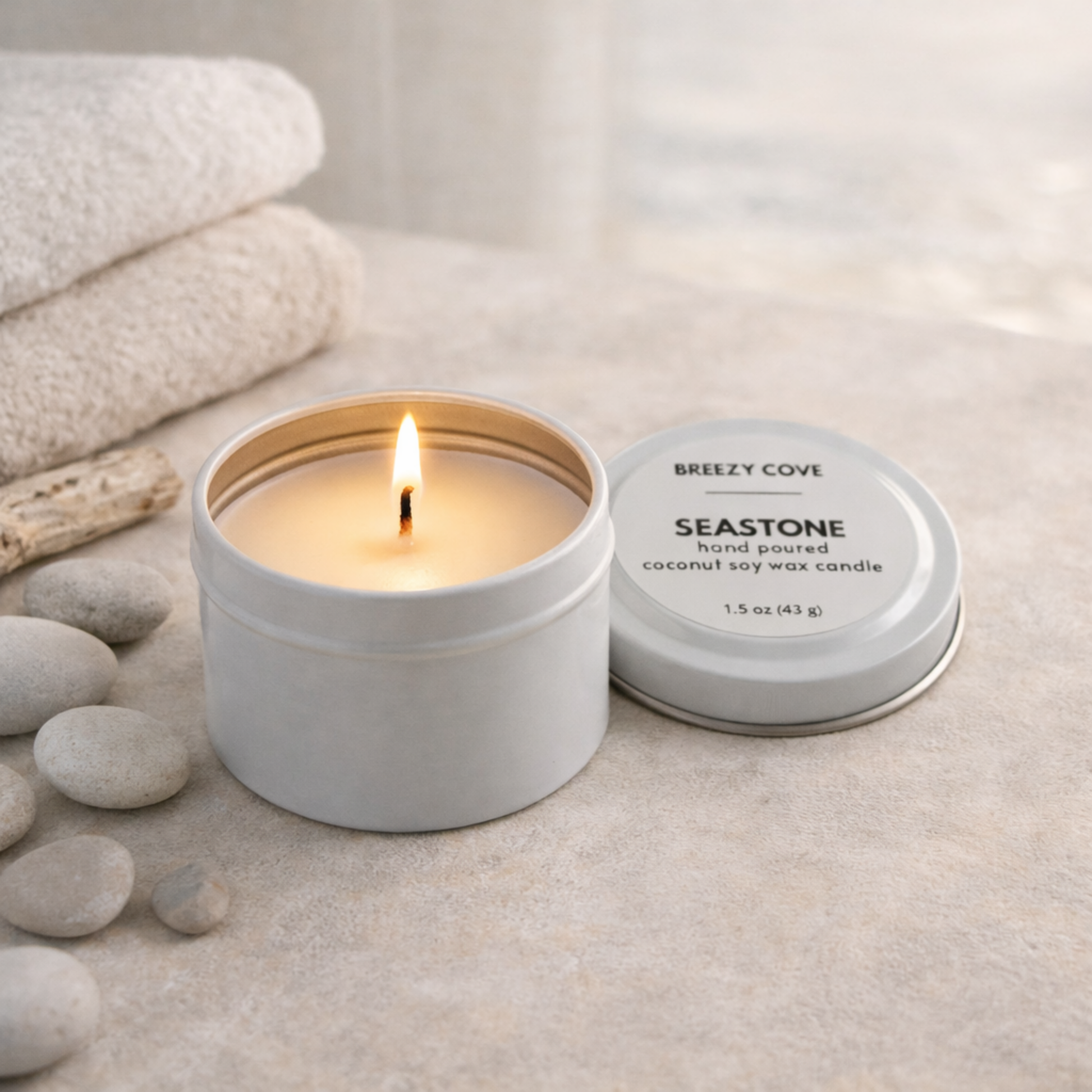 Seastone beach scented mini candle tin with in a beach spa setting for a calm coastal scent.