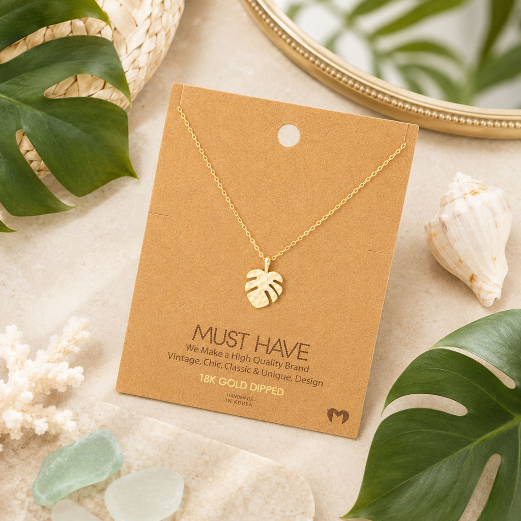 Dainty gold monstera necklace on jewelry card styled with tropical beach accents — 18k gold dipped beach necklace for women