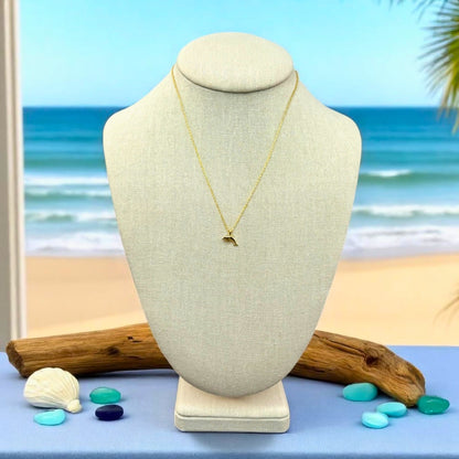 dainty gold dolphin beach Necklace on a mannequin bust with a beach background