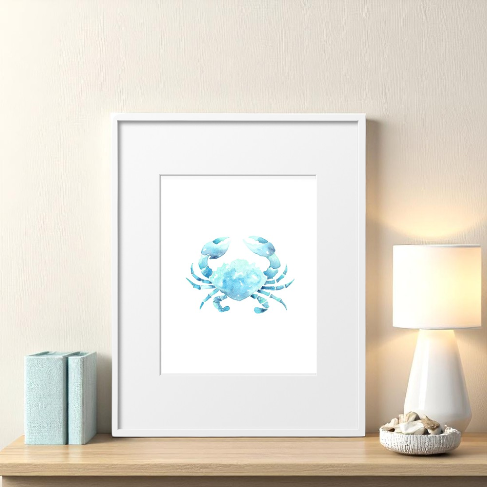 Single 8x10 framed crab art print on a soft neutral wall above a small coastal table, styled with seashells, a ceramic lamp, and beachy home decor in a relaxed bedroom or entryway setting.