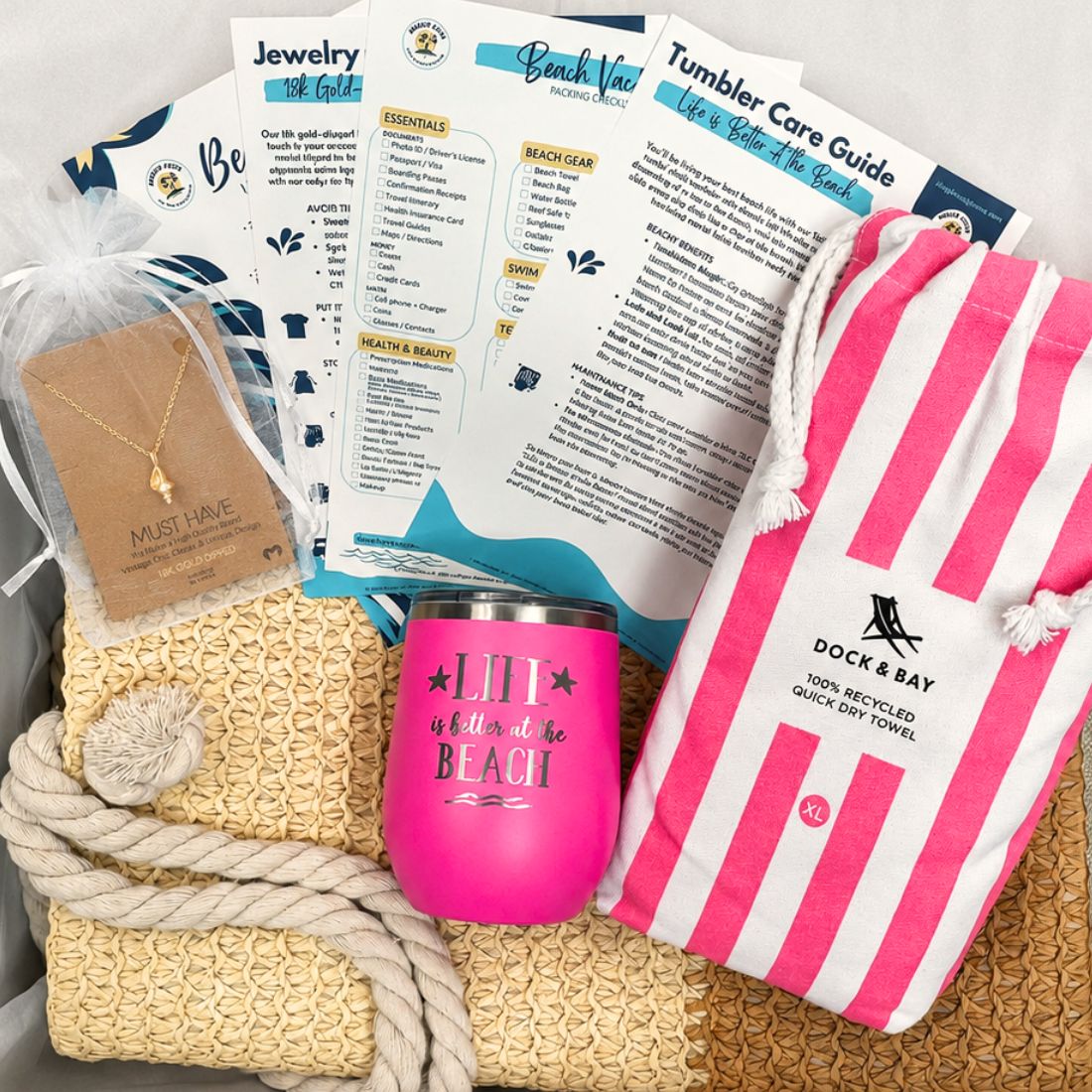 Gift-ready pink beach gift set boxed with straw beach bag, pink striped towel, pink tumbler, gold-dipped conch shell beach necklace and bonus cards.