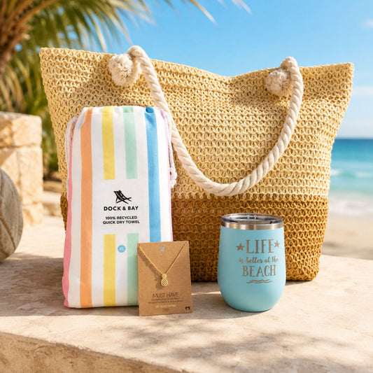 Pastel beach bag gift set for beach lovers with straw beach bag, pastel striped towel, blue tumbler and gold-dipped pineapple necklace by the ocean.