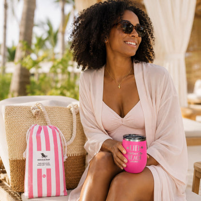 Pink beach lover beach bag gift set for women with straw beach bag, quick dry beach towel, tumbler, and gold dipped conch shell necklace in a relaxing resort setting