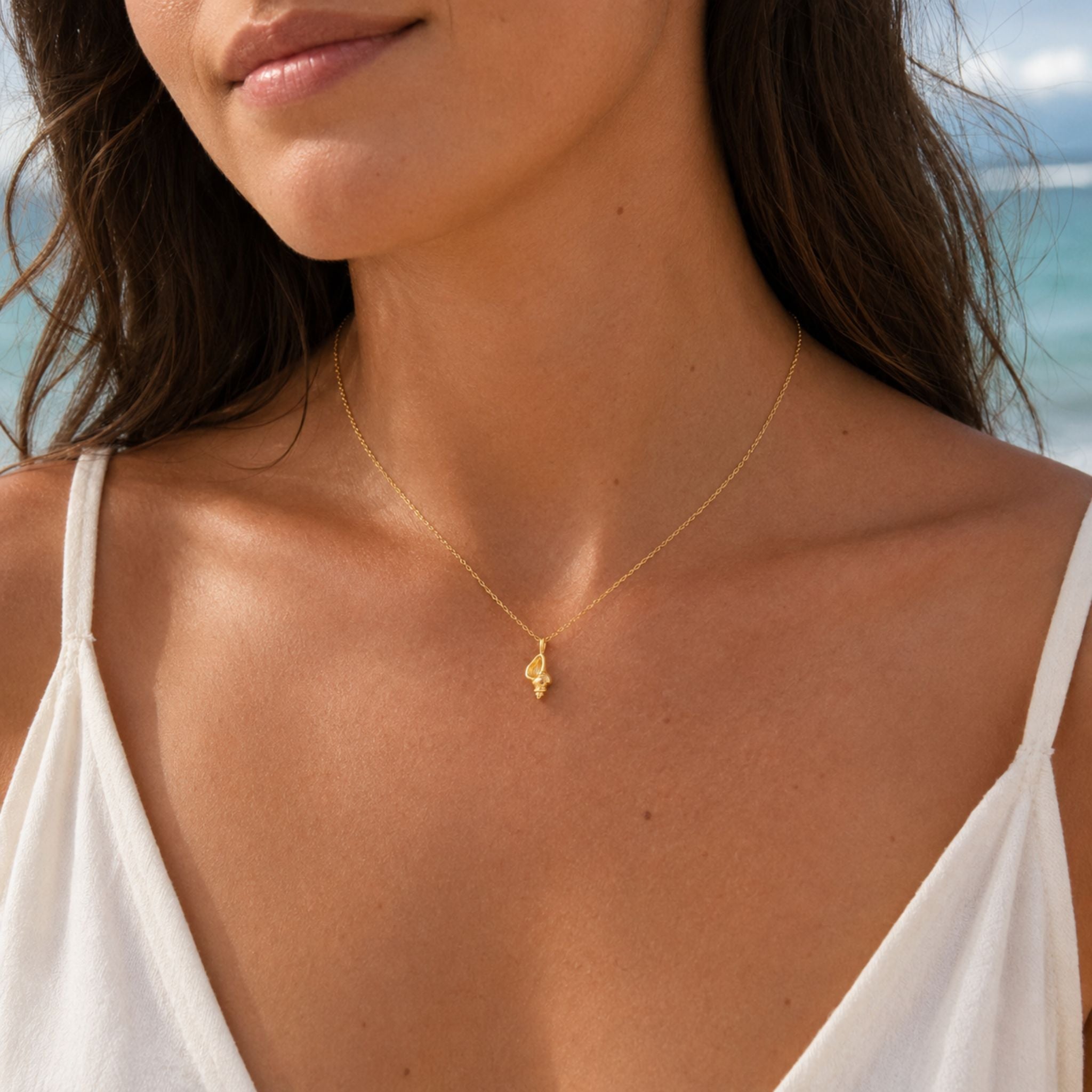Woman wearing a dainty gold conch shell necklace at the beach — 18k gold dipped conch shell jewelry for women
