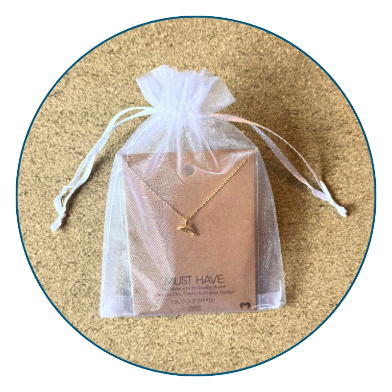 Gold dolphin necklace in sheer white organza gift bag with ribbon, perfect for gifting or safe storage.
