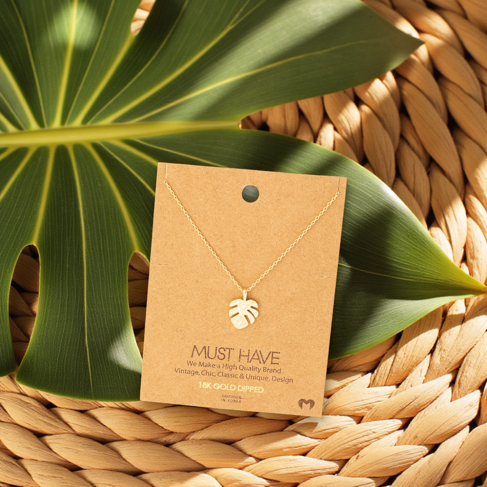 18k gold dipped monstera necklace styled with tropical-inspired accents for women who love the beach.