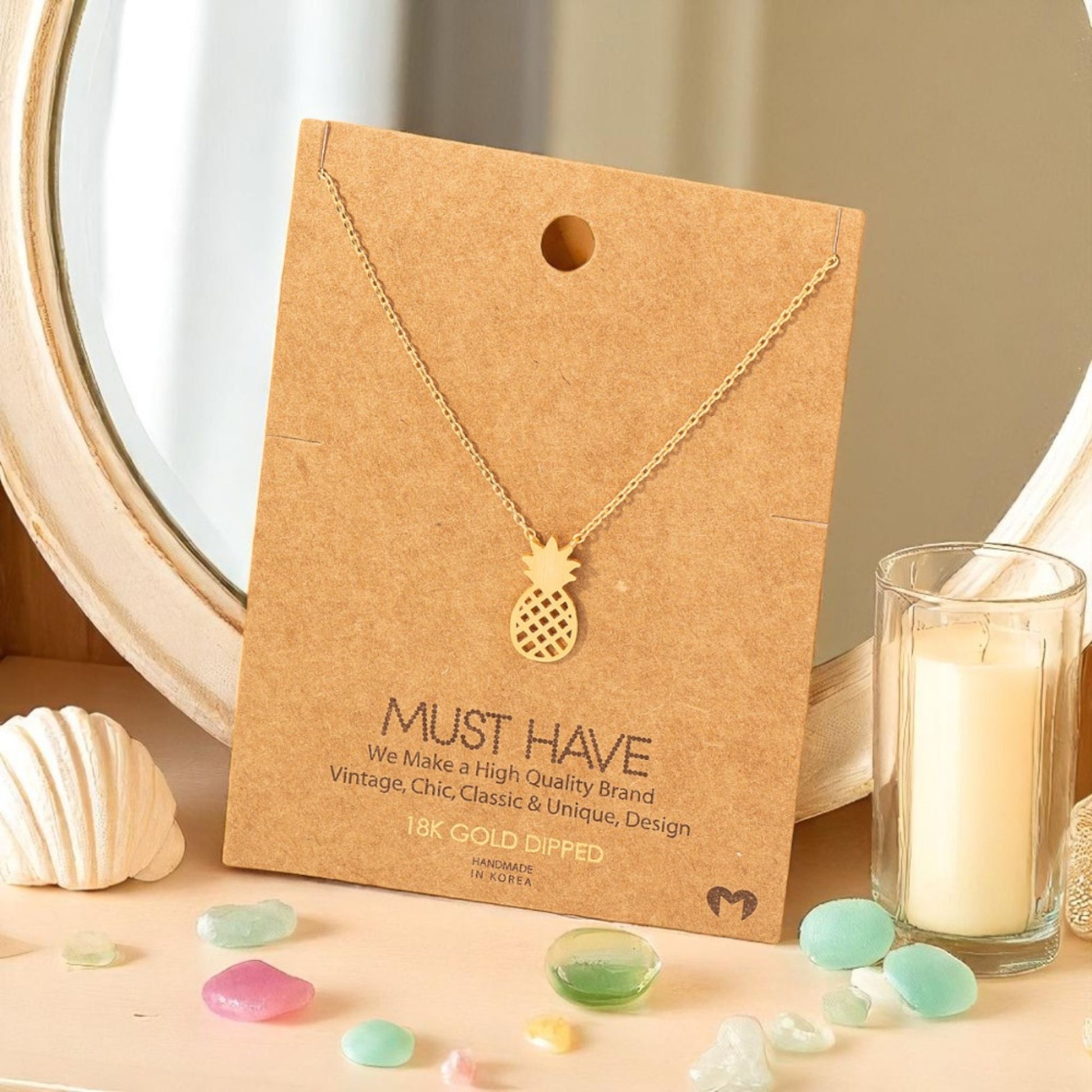 Dainty gold minimalist pineapple necklace styled on a beach vanity with sea glass, sunshine and calm.