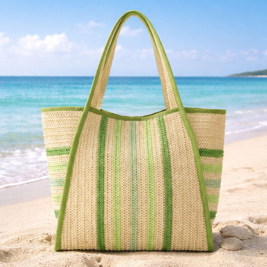 Green striped straw beach tote bag on the sand with an ocean background.