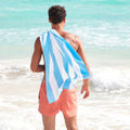 man with light blue striped microfiber beach towel on the beach, designed to be quick dry, sand free, lightweight, and easy to pack