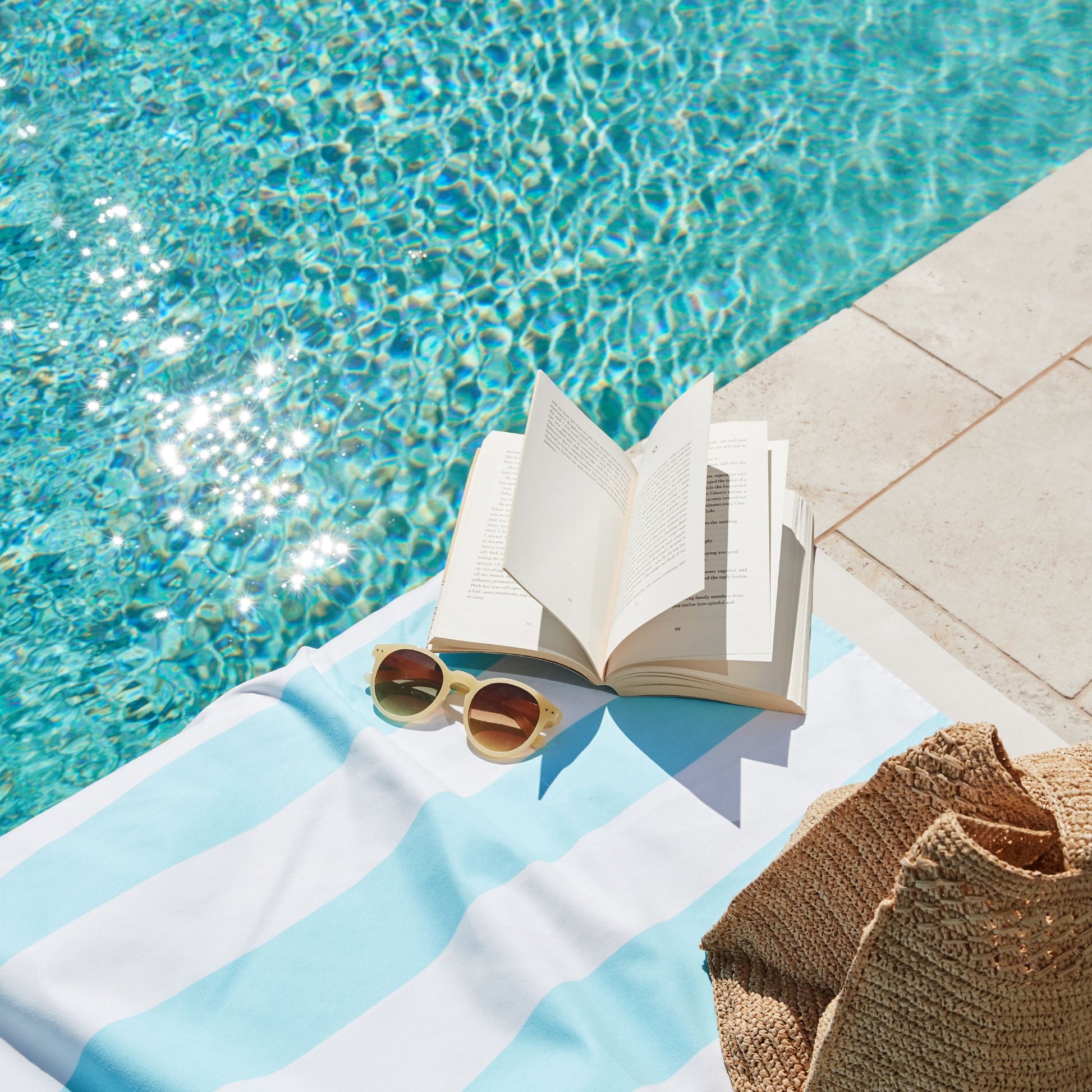 A light blue striped microfiber beach towel poolside during vacation