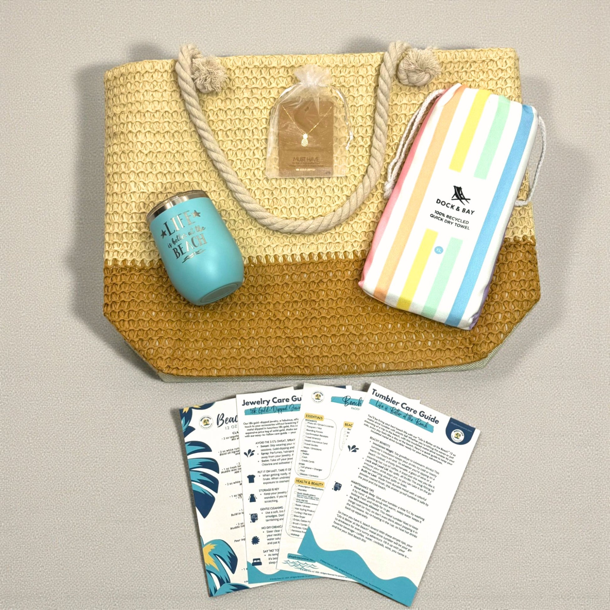 Flat lay of Pastel Beach Lover Gift Set with straw beach bag, pastel striped towel, teal tumbler, pineapple necklace, and printed bonuses.