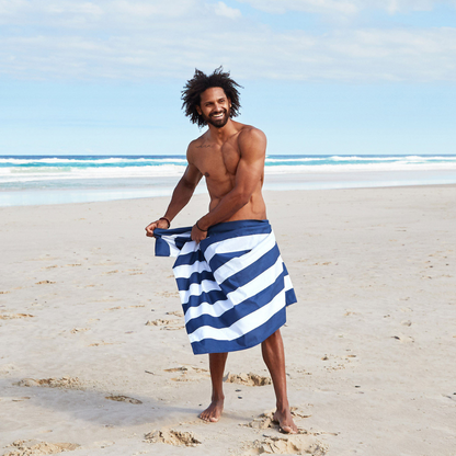 man on beach wrapped in navy blue and white striped quick dry Dock and Bay extra large beach towel