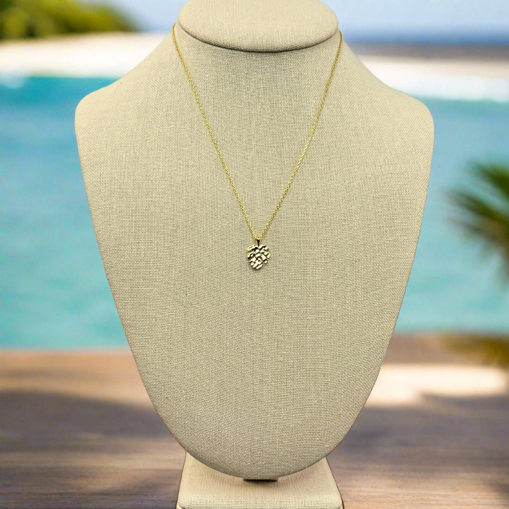 monstera tropical leaf pendant necklace 18k gold dipped necklace is perfect jewelry accessory for beach lovers on linen jewelry display with an ocean background