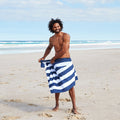 Navy and white striped microfiber beach towel on the beach, designed to be quick dry, sand free, and easy to pack